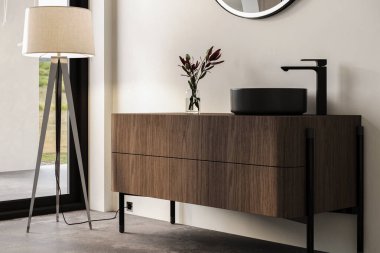 Beyaz duvarlı modern banyo, oval aynalı siyah lavabo, küvet, gri beton zemin. Minimalist parlak banyo ve modern mobilyalar.