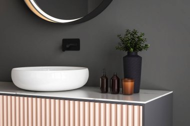 Lavaboyu kapat, oval ayna siyah duvarda asılı, mermer tezgah.