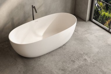 Siyah musluğu olan beyaz bir küvet fayanslı zeminde oturur. Banyo modern bir tasarıma ve pencerenin dışındaki ağaçlara bakıyor.