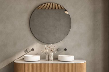 Büyük aynalı ve lavabolu bir banyo. Ayna yuvarlaktır ve camdan yapılmıştır. Lavabo beyaz ve altında ahşap bir dolap var.