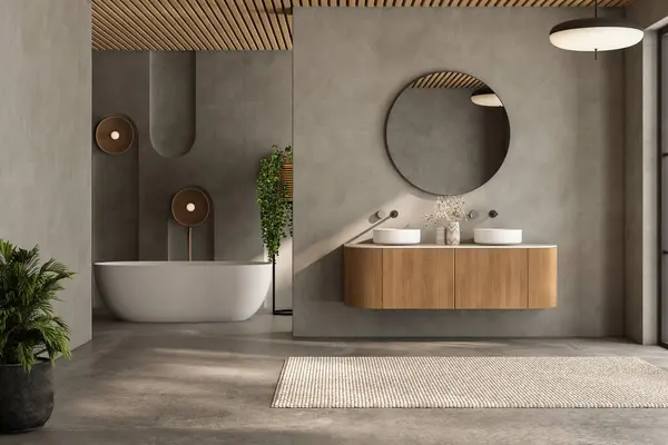 Büyük aynalı ve beyaz küvetli bir banyo. Banyo temiz ve iyi aydınlatılmış, yerde bir halı ve köşede bir saksı bitkisi var. Manzara sakin ve rahatlatıcı.