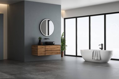 Modern banyo içi mavi ve beyaz tonlu duvar, beton zemin, siyah lavabo ve oval aynalı ahşap kibir, beyaz küvet, panoramik pencereler.
