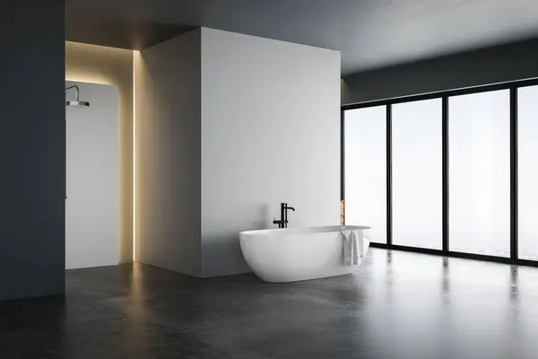 stock image Bright bathroom interior with white tones wall, concrete floor, wooden vanity with black sink and oval mirror, white bathtub, panoramic windows.