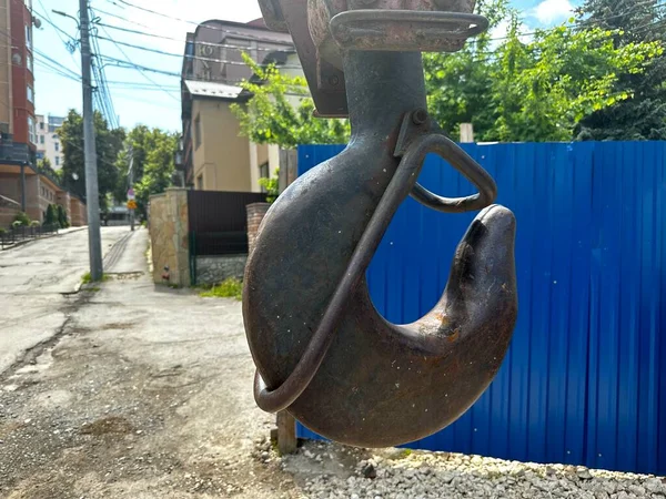 stock image The hook of a construction crane close-up on the background of a city street. Construction machine crane hook for lifting heavy construction materials and equipment. A large metal hook on the boom of the crane