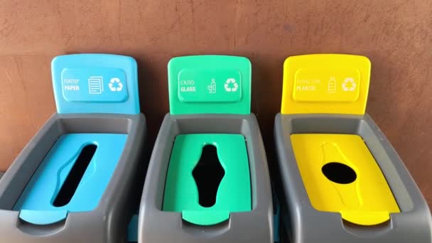 さまざまな種類のゴミを分類するための碑文のペーパー ガラス プラスチックが付いている多色のプラスチックごみ缶 プラスチックビン ゴミ缶 リサイクル カラーボックス ゴミの分類 自然環境の保全について エコロジーアプローチ — ストック動画