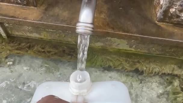 用从装有水龙头的泉水中流出的新鲜 清洁的水填充一个白色的罐子 水龙头一种金属水龙头 泉水从其上流入一个白色的水箱来自自然水源的饮用水 — 图库视频影像