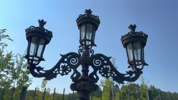 墓地附近一个被蜘蛛网覆盖的锻造的黑色三重灯笼 阳光灿烂的街道上神秘的老式灯笼 古董灯 花园及公园灯笼 — 图库视频影像