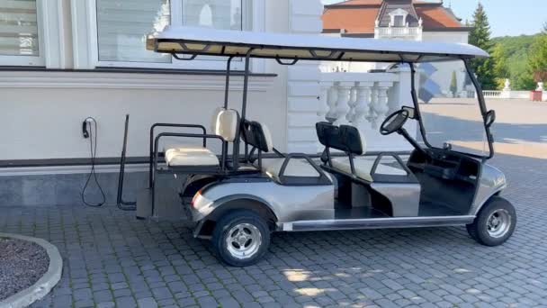 ゴルフカートは ホテルの近くの庭の電気充電ステーションに駐車されています 高級リゾートのゴルフカートは 観光客がゴルフコースに連れて行くのを待っています — ストック動画