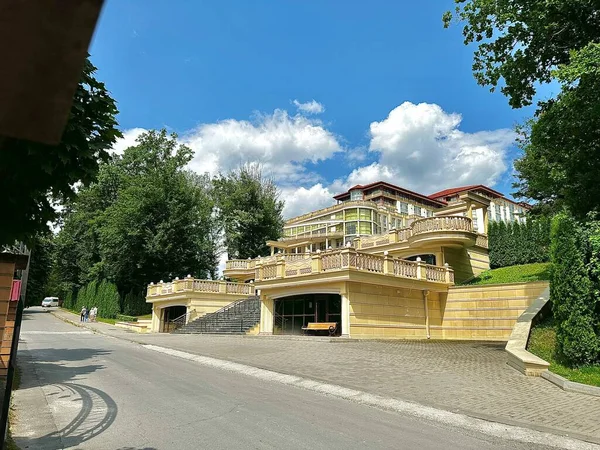 A modern building of a luxury spa hotel in the middle of a green park on a sunny summer day. A hotel in the form of a palace in a natural park. Rest in an expensive hotel