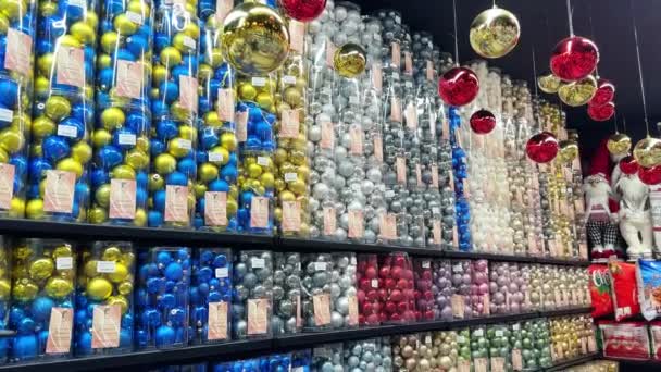 许多五彩缤纷的圣诞树球可以在商店的圣诞商店货架上挑选 超市大厅里圣诞树的装饰品 一面装有玻璃圣诞球的墙 — 图库视频影像