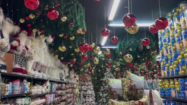 カラフルな新年とクリスマスのお土産とギフトの大規模な装飾市場 ギフトやおもちゃで新年のクリスマスショップ 店でクリスマスプレゼントを買う 枝にクリスマスツリーボール — ストック動画