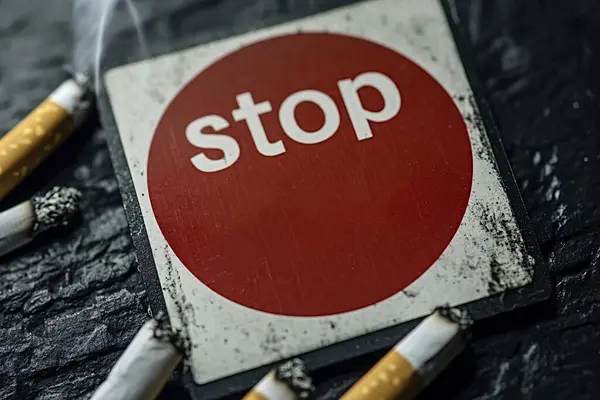 stock image Circle of extinguished cigarettes surrounds a stop smoking sign, urging viewers to kick the habit