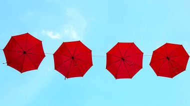 Mavi gökyüzünün arka planında kırmızı şemsiyeler.