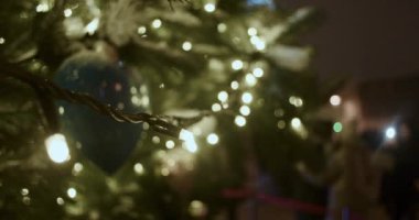 Şehrin merkez meydanındaki bir Noel ağacının dallarında sıcak ve parlak ışıklar.