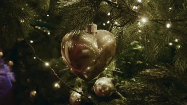 Close Ouro Brilhando Bola Ano Novo Forma Coração Pende Árvore — Vídeo de Stock
