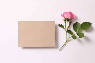 blank card with pink rose flower and envelope. top view with copy space. flat lay, minimal style, mockup.