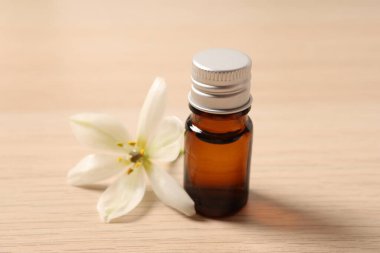 essential essential oil in bottle on wooden background, close up