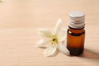 bottle with beautiful essential oil on light wooden table