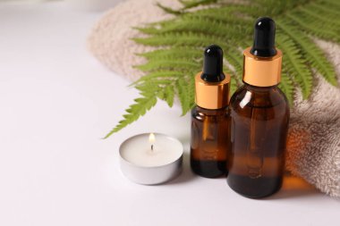 bottles with essential oil and flowers on table