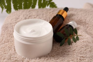 Hafif arka planda okaliptüs yaprağı olan bir şişe kozmetik kremi.