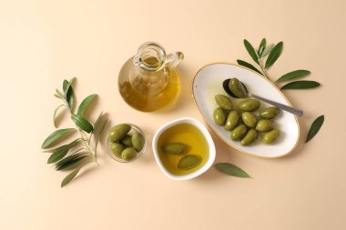 Beyaz zemin üzerinde zeytin yağı, zeytin ve zeytin dalı içeren kompozisyon