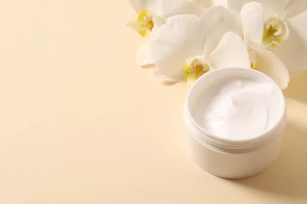 cosmetic container for face care, white cream, cream and orchid leaf on a white background.