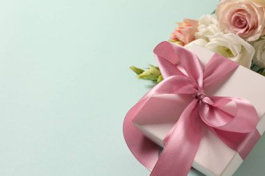 Güzel bir buket çiçek ve hediye paketi açık gri masada, üst manzarada yazı için yer var. Anneler Günü kutlaması.