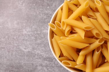 Açık gri arka planda kaşıkla kasede makarna ve mesaj için yer var. üst yaşam