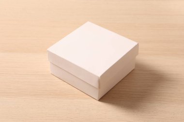 Ahşap arka plan üzerinde beyaz karton kutu.