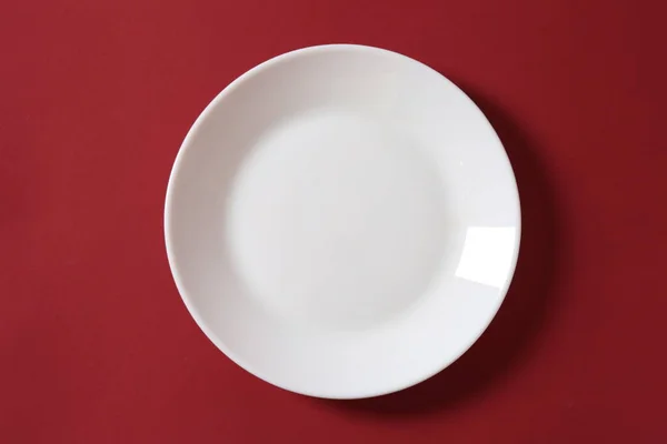 Weißer Teller Auf Rotem Tisch Freier Platz Für Text Draufsicht — Stockfoto