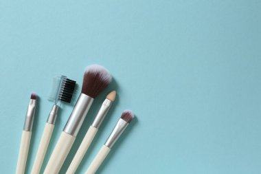 farklı boyutlarda makyaj fırçaları ve pembe arka planda gölgeler.