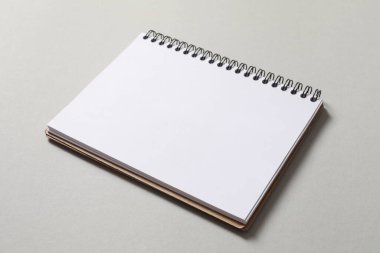 Gri arkaplan üzerinde boş bir kağıt olan defter.