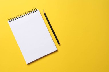 Sarı arkaplanda sarı kalemle izole edilmiş boş not defteri