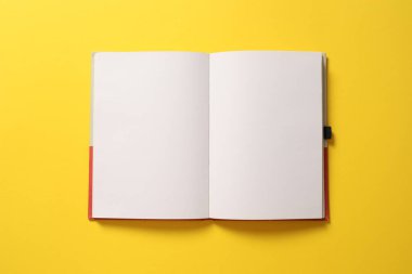 Parlak sarı arkaplanda boş bir not defteri aç. Düz yat. Kopyalama alanı olan üst görünüm.