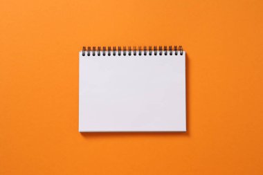 Turuncu duvarda kağıt bir not. boş not defteri.