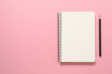 Boş sayfalı defter ve pembe arka planda kalem, üst manzara. Düz yat. Metin için boşluk