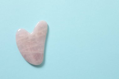 Mavi arkaplanda pembe taşlardan yapılmış bir kalp şekli..