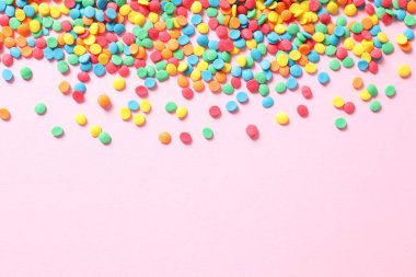 Pembe arka planda renkli şeker parçacıkları ve konfeti