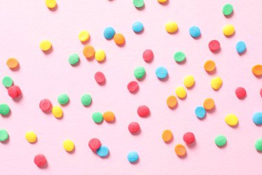 Pembe arka planda renkli tatlılar. Üst Manzara. Boşluğu kopyala.