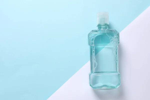 bottle of soap with foam on light blue background, flat lay. space for text