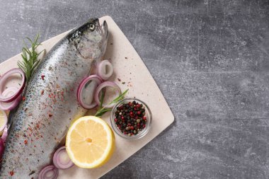 Gri arkaplanda taze gökkuşağı alabalığı.