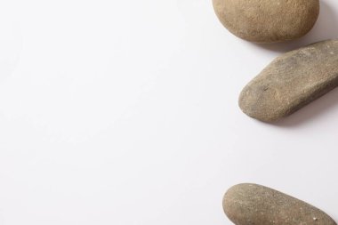 Beyaz zemin üzerinde fotokopi alanı olan çakıl taşları. Üst görünüm, zen ve uyum.