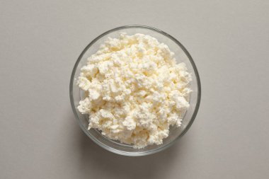 Gri arka planda pişmemiş süzme peynir kasesi..