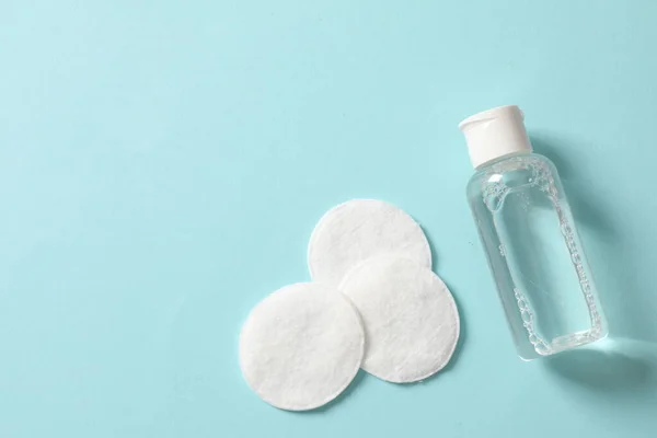 cosmetic bottle and cotton pads on a blue background. top view. copy space