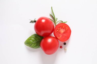 Beyaz arka planda izole edilmiş taze domates ve fesleğen yaprakları