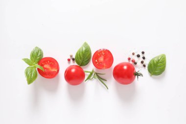 Beyaz arka planda taze kırmızı kiraz domatesleri ve yeşil yapraklar. Üst görünüm, boşluk kopyala.