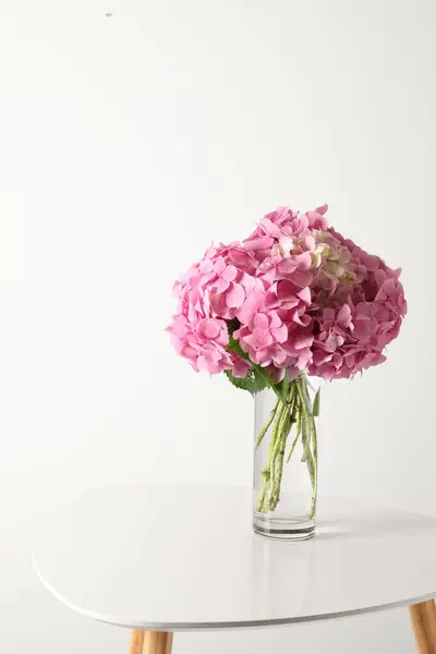 vase with beautiful flowers on table against light background