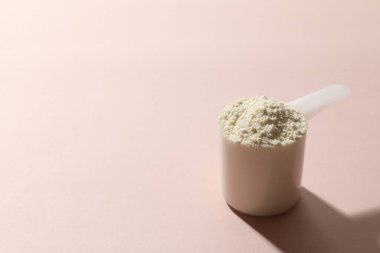 Doğal yoğurtlu cam, kaşık ve toz, bej arka planda.