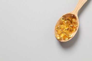 Omega-3 kapsüllerinin ahşap kaşığı mavi arka planda, kopyalanmış. Sağlık, refah ve takviyeler..