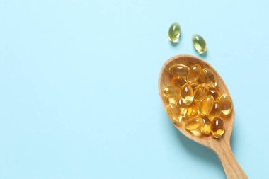 Omega-3 kapsüllerinin ahşap kaşığı mavi arka planda, kopyalanmış. Sağlık, refah ve takviyeler..